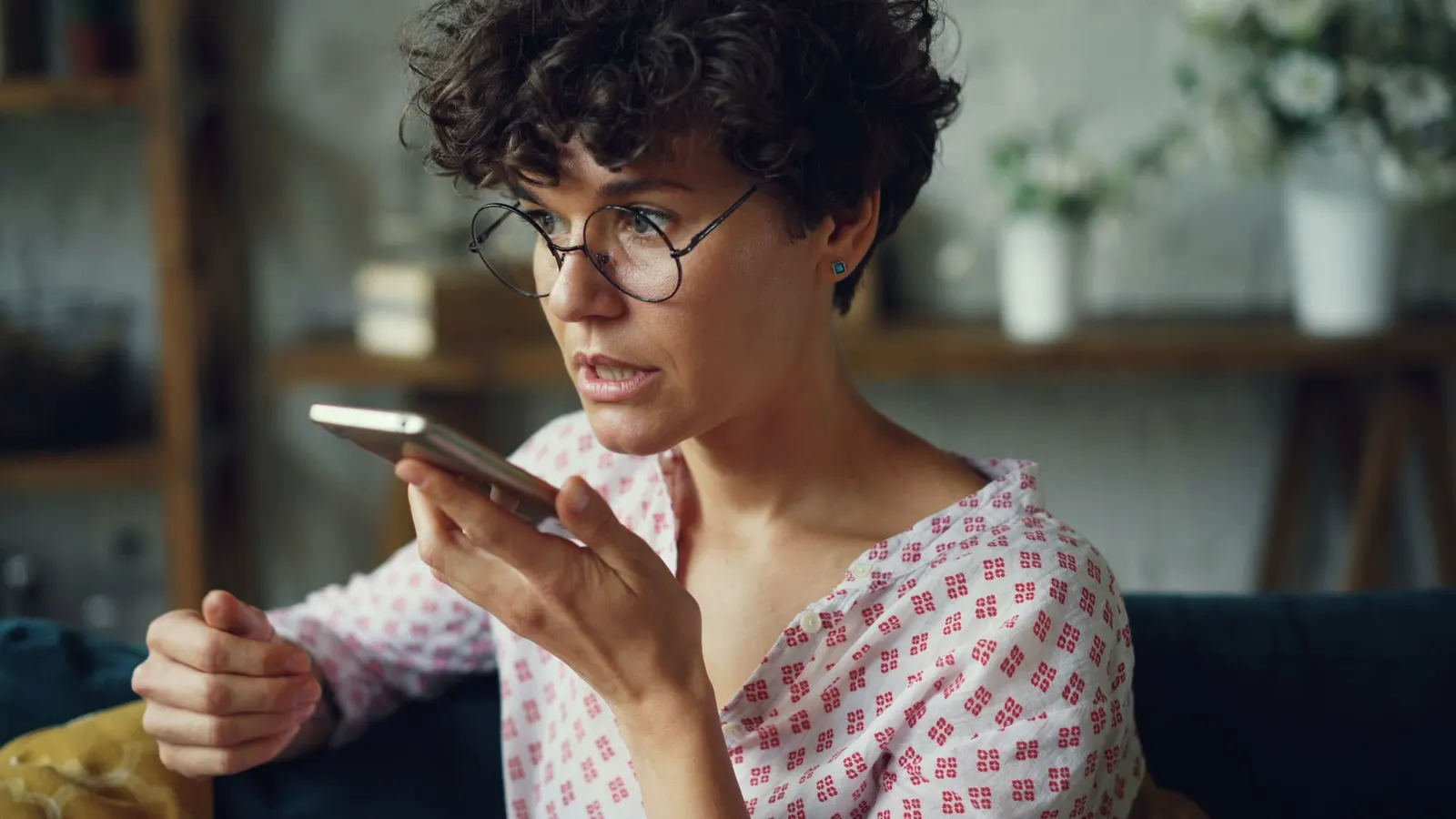 A woman dictates a message to her phone at home